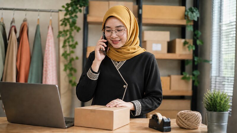E-commerce seller packing an order while on the phone